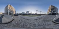 a wide angle 360 - lens shot showing the buildings with circular shapes in them against a clear sky