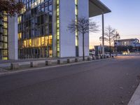 this is a large white building with windows on the side of the building and some trees and benches