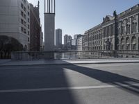 a long street in an urban area, with many buildings in the background and people crossing over it