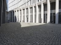 a stone courtyard in the middle of a building with several windows, is light reflecting off of the tiles