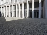 a stone courtyard in the middle of a building with several windows, is light reflecting off of the tiles