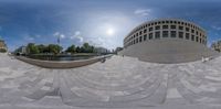 fisheye lens of a circular walkway at the base of a building next to a river