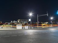 large building on the street with lights in front and other buildings nearby at night with no one moving