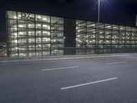 a large long building with lights on the side of it by a street with cars