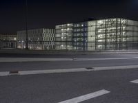 a large long building with lights on the side of it by a street with cars