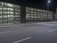 a large long building with lights on the side of it by a street with cars