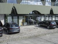 an image of an outdoor view of three different cars parked next to each other and in front of the building