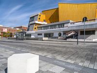 a concrete block on the sidewalk in front of a yellow building and another concrete block on a sidewalk