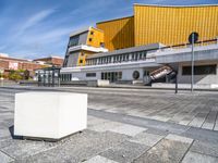 a concrete block on the sidewalk in front of a yellow building and another concrete block on a sidewalk