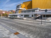 a concrete block on the sidewalk in front of a yellow building and another concrete block on a sidewalk