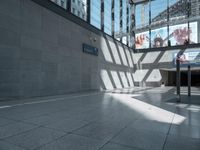 the building has a glass ceiling and a stone floor with light shining in from the windows