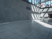 the building has a glass ceiling and a stone floor with light shining in from the windows