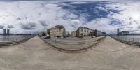 fish eye view of buildings on a street near the water with a boat in the background