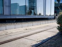 a train track that is next to a large building with glass windows and brick floors