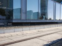 a train track that is next to a large building with glass windows and brick floors