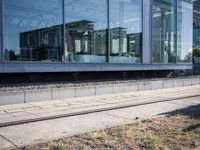 a train track that is next to a large building with glass windows and brick floors