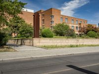 a large brick building sits on the side of a street near a paved street in front of it