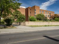 a large brick building sits on the side of a street near a paved street in front of it