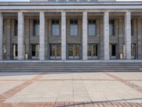 a row of stairs outside of a building with columns on each side of the entrance