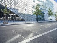 a modern building has glass architecture on both sides of the road and sidewalk outside it