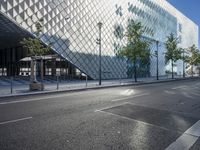 a modern building has glass architecture on both sides of the road and sidewalk outside it