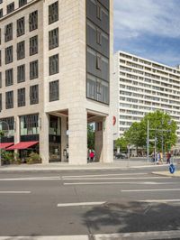 an image of a tall, modern building at the street corner with people walking and on the street