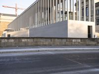 the large, empty sidewalk with multiple columns in front of the building with two signs