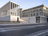 the large, empty sidewalk with multiple columns in front of the building with two signs