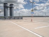 parking lot with two empty street signs and two tall, gray poles on the side