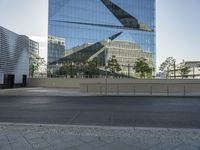 a large glass building in a city with no people on the street or in front