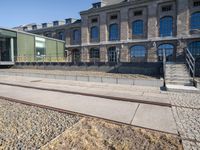 there is no image here to provide a caption for? a train track to the right is in front of a large building