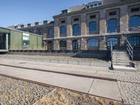 there is no image here to provide a caption for? a train track to the right is in front of a large building