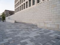 a white building with bricks surrounding it and sidewalk in front of it with stairs leading into