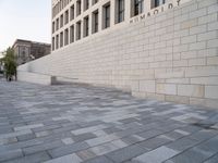 a white building with bricks surrounding it and sidewalk in front of it with stairs leading into