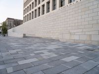 a white building with bricks surrounding it and sidewalk in front of it with stairs leading into