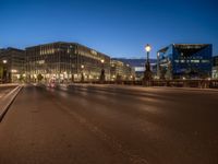 the city skyline is at night from the street level with traffic and pedestrians walking on it