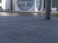 there is a man standing next to a fountain and water feature in front of a building