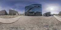 fish eye view of modern office buildings and cobblestones in a city with blue sky