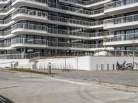 there are a number of motorcycles parked on the street near a large white building with balcon