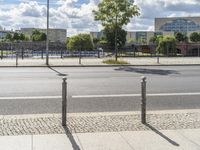 a street with lots of grass and trees in the background and two poles standing on it