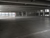 an empty parking garage with a metal floor and a clock on the wall above the doorway