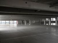 an empty parking garage with a metal floor and a clock on the wall above the doorway