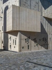 cobblestone driveway surrounded by modern buildings on sunny day with sun reflecting onto the windows