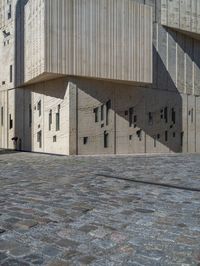 cobblestone driveway surrounded by modern buildings on sunny day with sun reflecting onto the windows