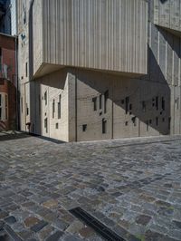 cobblestone driveway surrounded by modern buildings on sunny day with sun reflecting onto the windows