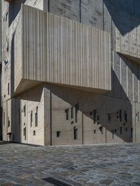 cobblestone driveway surrounded by modern buildings on sunny day with sun reflecting onto the windows