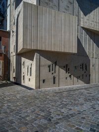 cobblestone driveway surrounded by modern buildings on sunny day with sun reflecting onto the windows