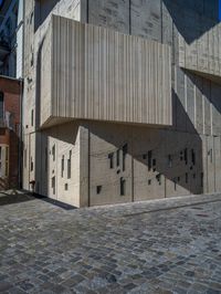 cobblestone driveway surrounded by modern buildings on sunny day with sun reflecting onto the windows