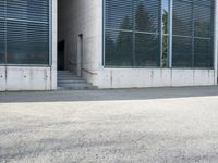 the black skateboard is in front of a tall building with lots of windows and concrete