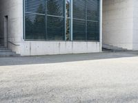 the black skateboard is in front of a tall building with lots of windows and concrete